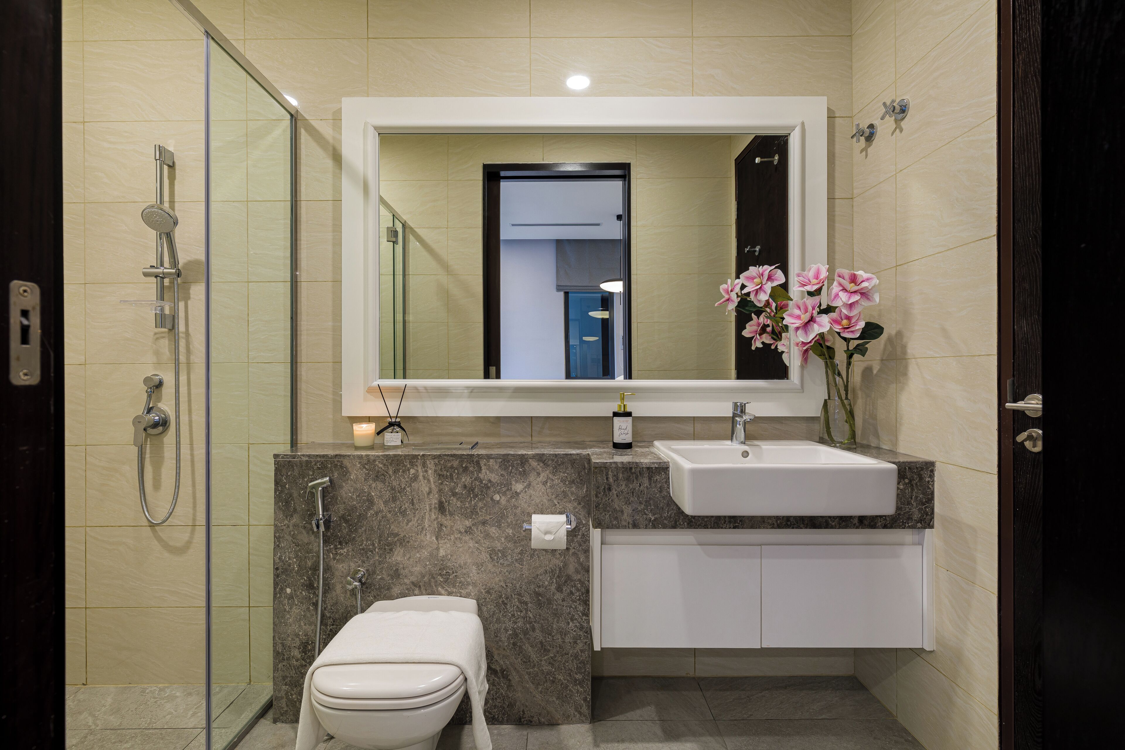Une salle de bain moderne avec une douche à parois de verre, des toilettes, un lavabo et un miroir au-dessus du lavabo.