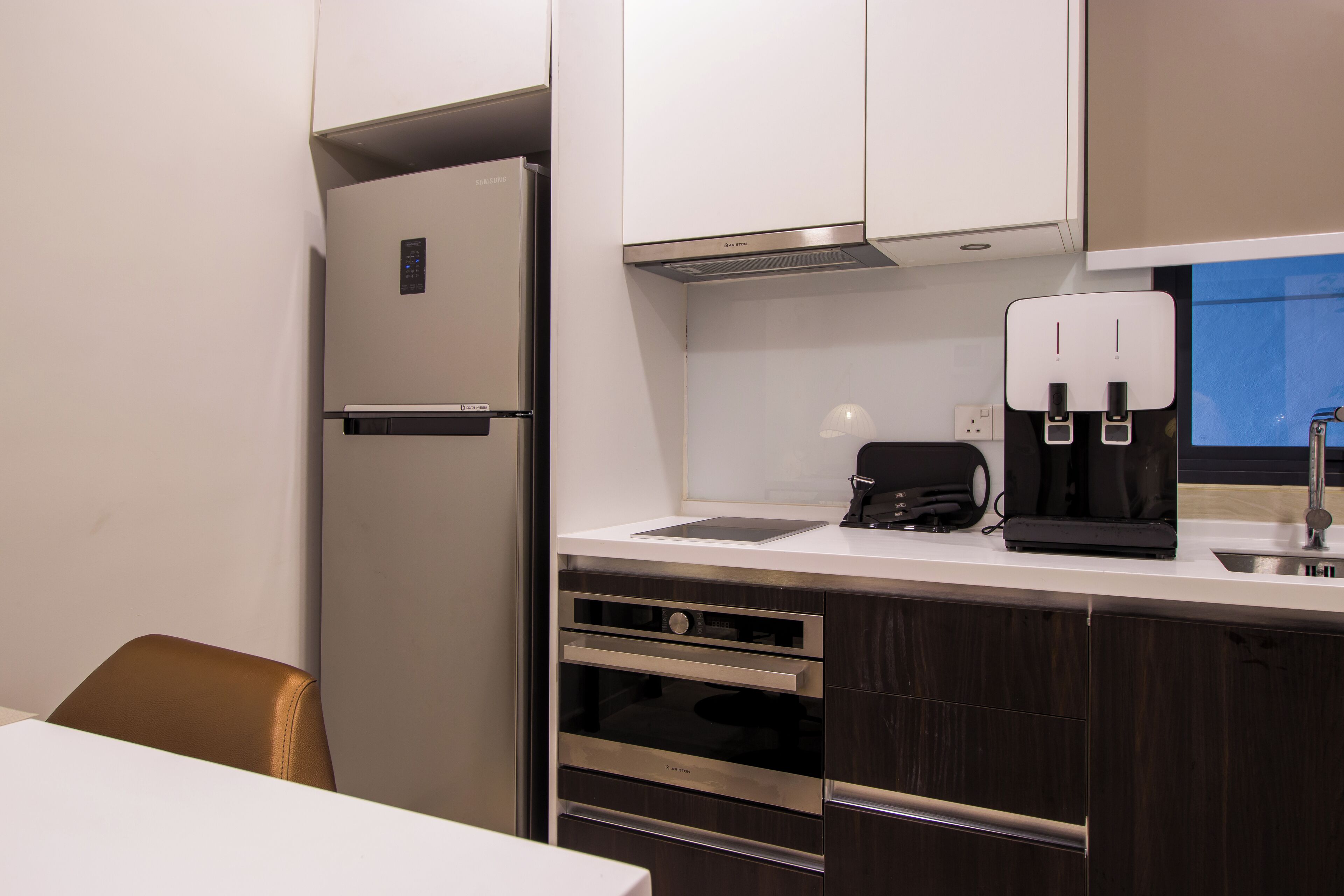 Una cocina moderna con refrigerador empotrado, cafetera y lavamanos.