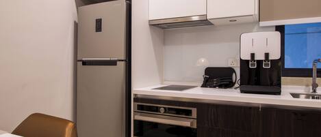 Una cocina moderna con refrigerador empotrado, cafetera y lavamanos.