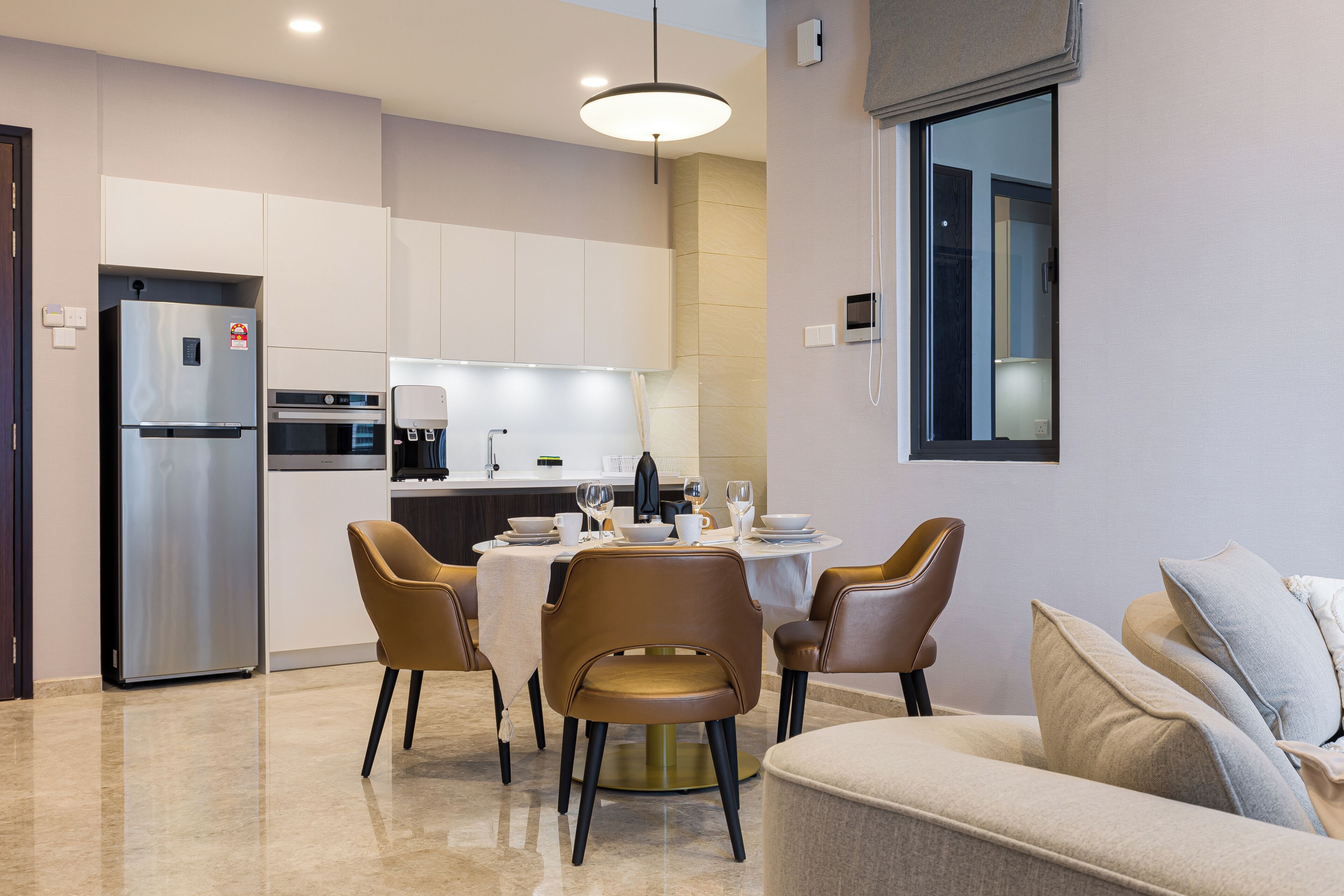 A modern kitchen with a dining area, including a table set for four, chairs, and a sofa.