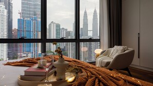 Una stanza moderna con un'ampia finestra che si affaccia su un panorama urbano, con grattacieli e le Torri Petronas.