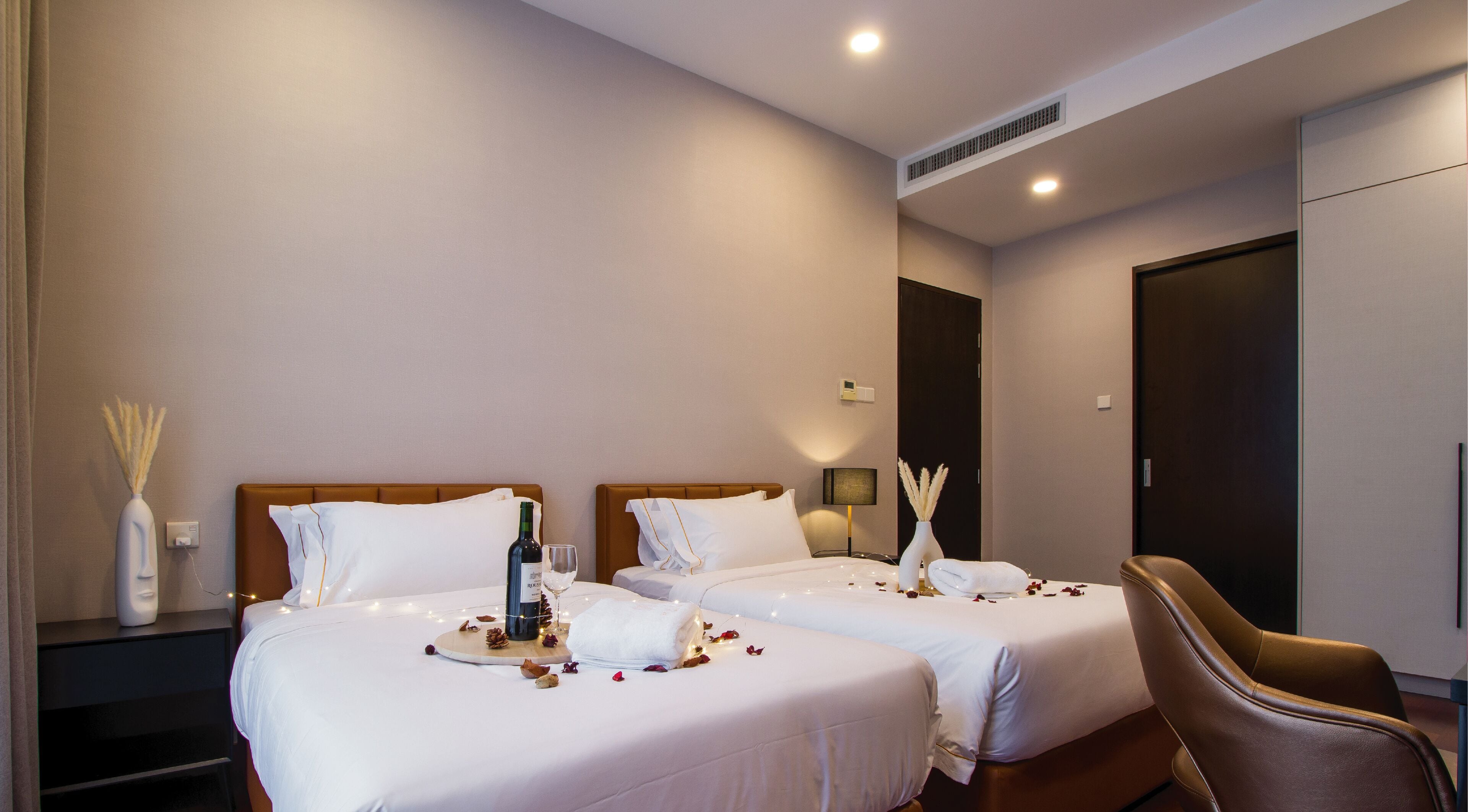 A hotel room with two beds, a nightstand, a chair, and a minibar.