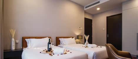 A hotel room with two beds, a nightstand, a chair, and a minibar.