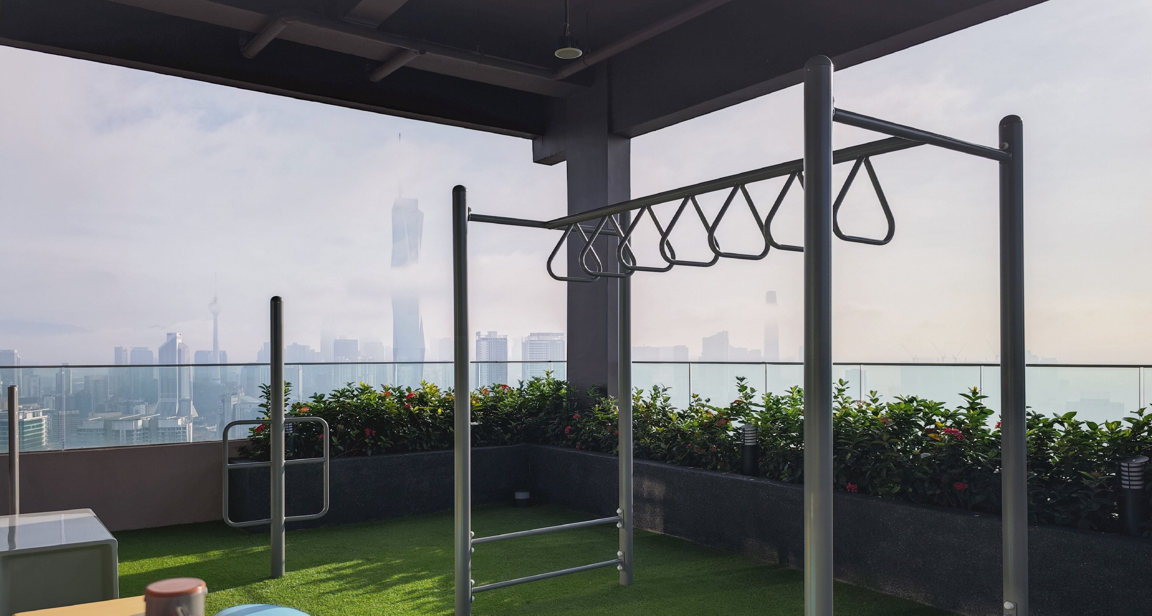 A rooftop terrace with a pull-up bar, a small table, and a chair.