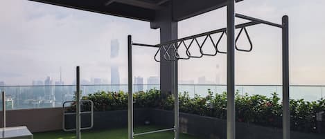 A rooftop terrace with a pull-up bar, a small table, and a chair.