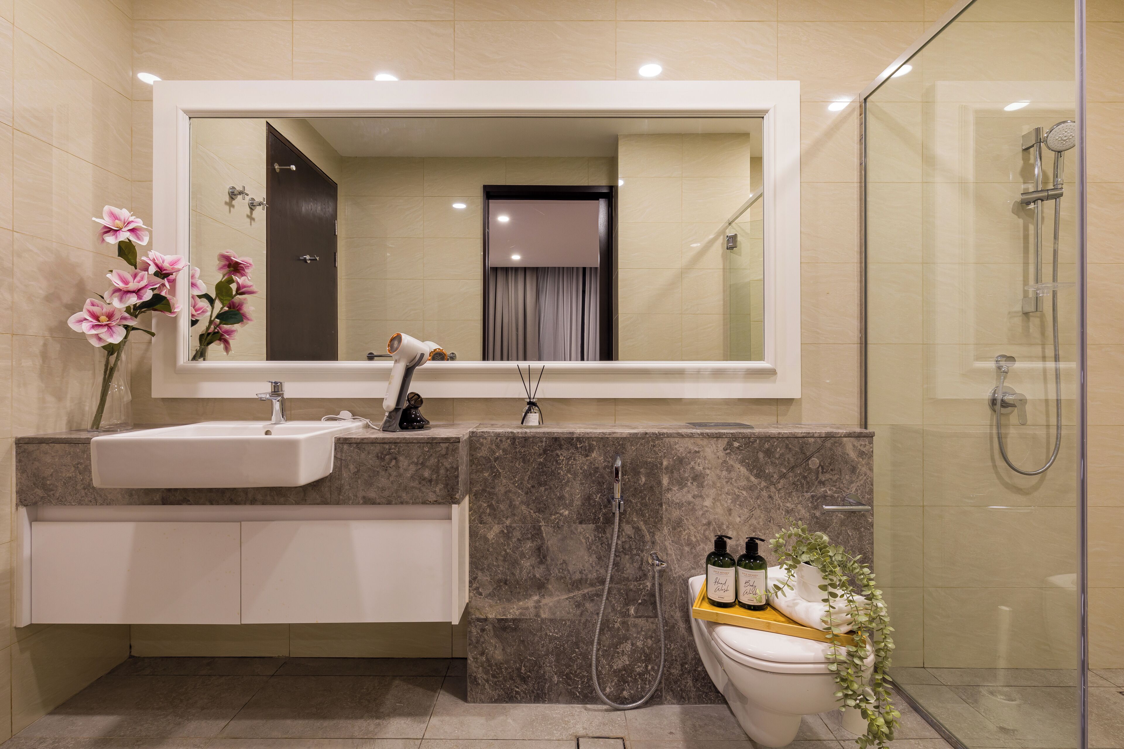 Un baño moderno con un espejo grande, un lavamanos, un inodoro y una ducha.