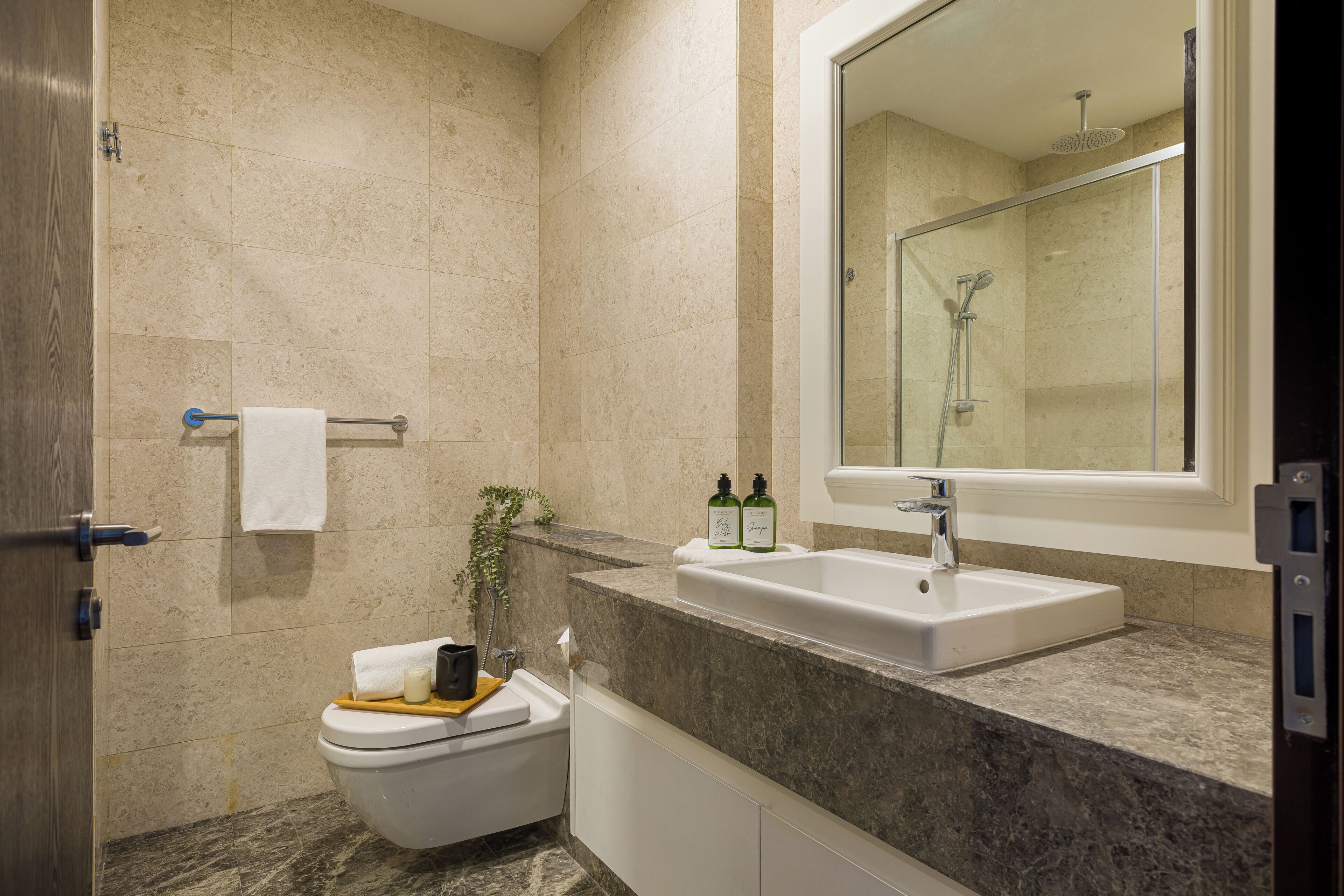 A modern bathroom with a marble sink, a glass shower enclosure, and a toilet.