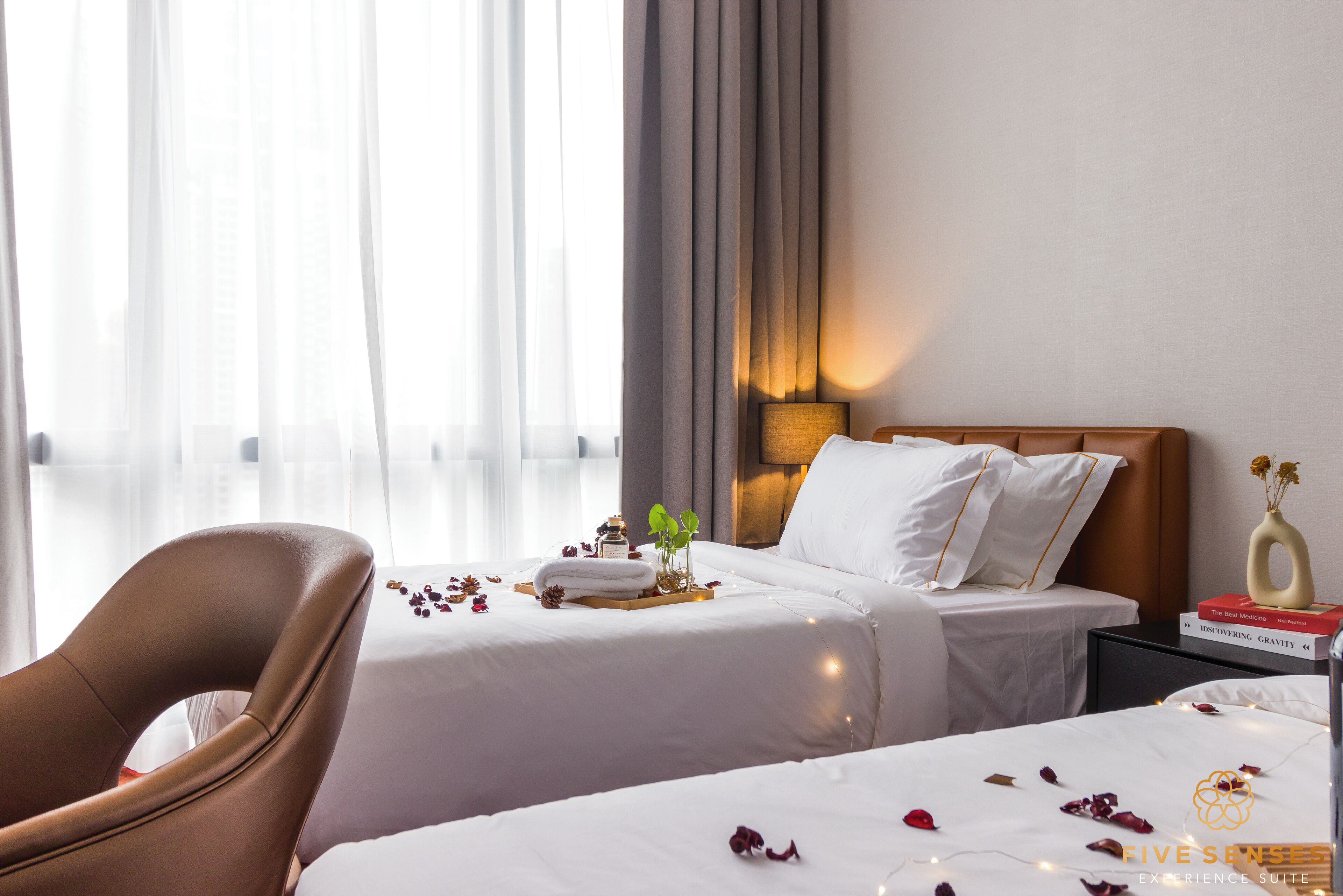 Une chambre d’hôtel avec deux lits, un coin salon et une table de chevet avec une lampe.