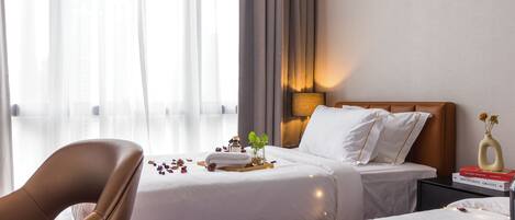 A hotel room with two beds, a sitting area, and a nightstand with a lamp.