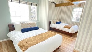 A hotel room with two beds, a large window, striped wallpaper, and wooden flooring. - Villa Sapporo Seiga (Sapporo)