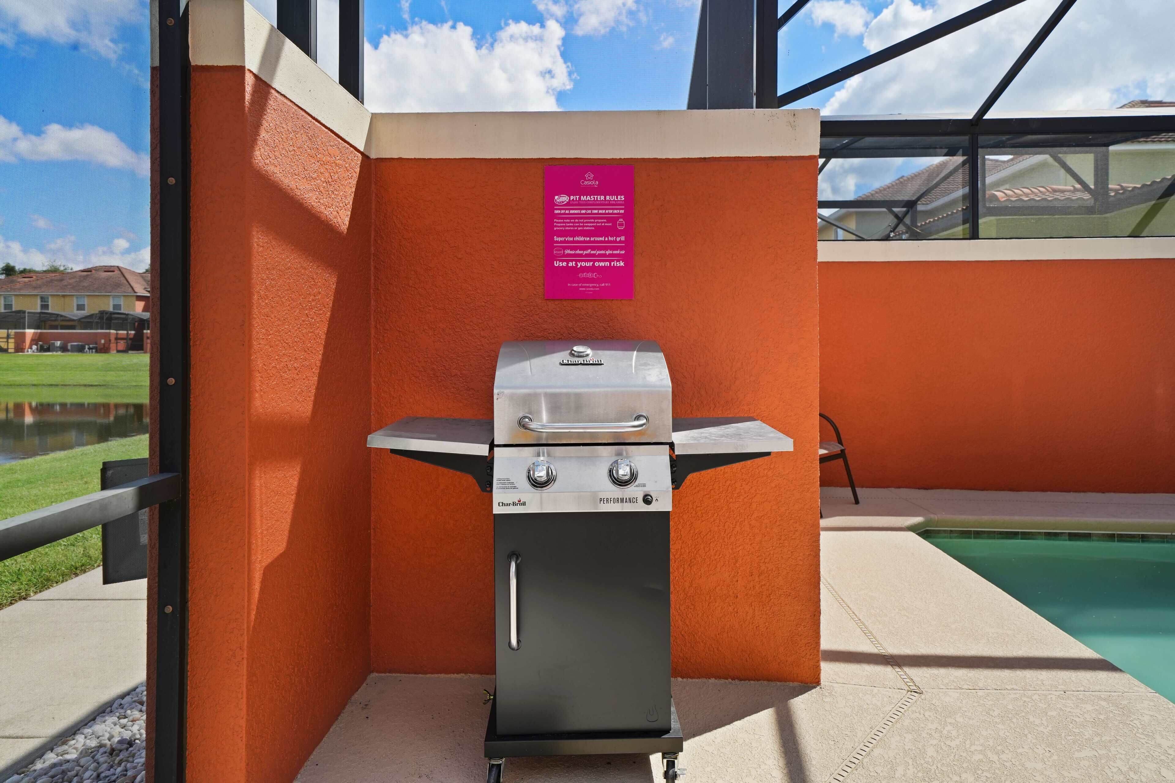 Un barbecue en acier inoxydable, installé dans un espace extérieur doté d’une piscine et offrant une vue sur un quartier résidentiel.
