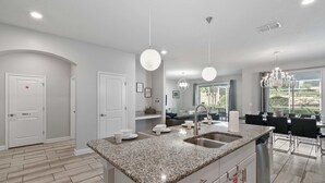 A modern kitchen with granite countertops, a double sink, and pendant lighting. - 1560 Tempo Lane (Davenport)