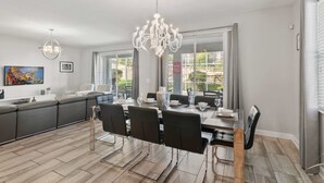 A modern kitchen with a dining area, large windows, and a chandelier. - 1560 Tempo Lane (Davenport)