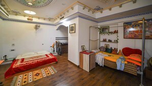 Una stanza con due letti, un angolo cottura e un soffitto decorato.