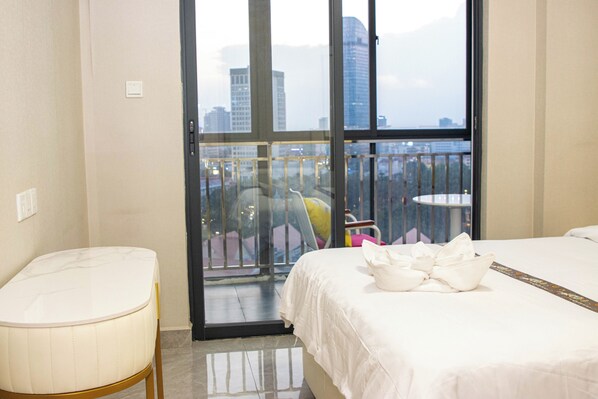 Une chambre d’hôtel avec un lit, une petite table et une vue sur la ville grâce à de grandes fenêtres.