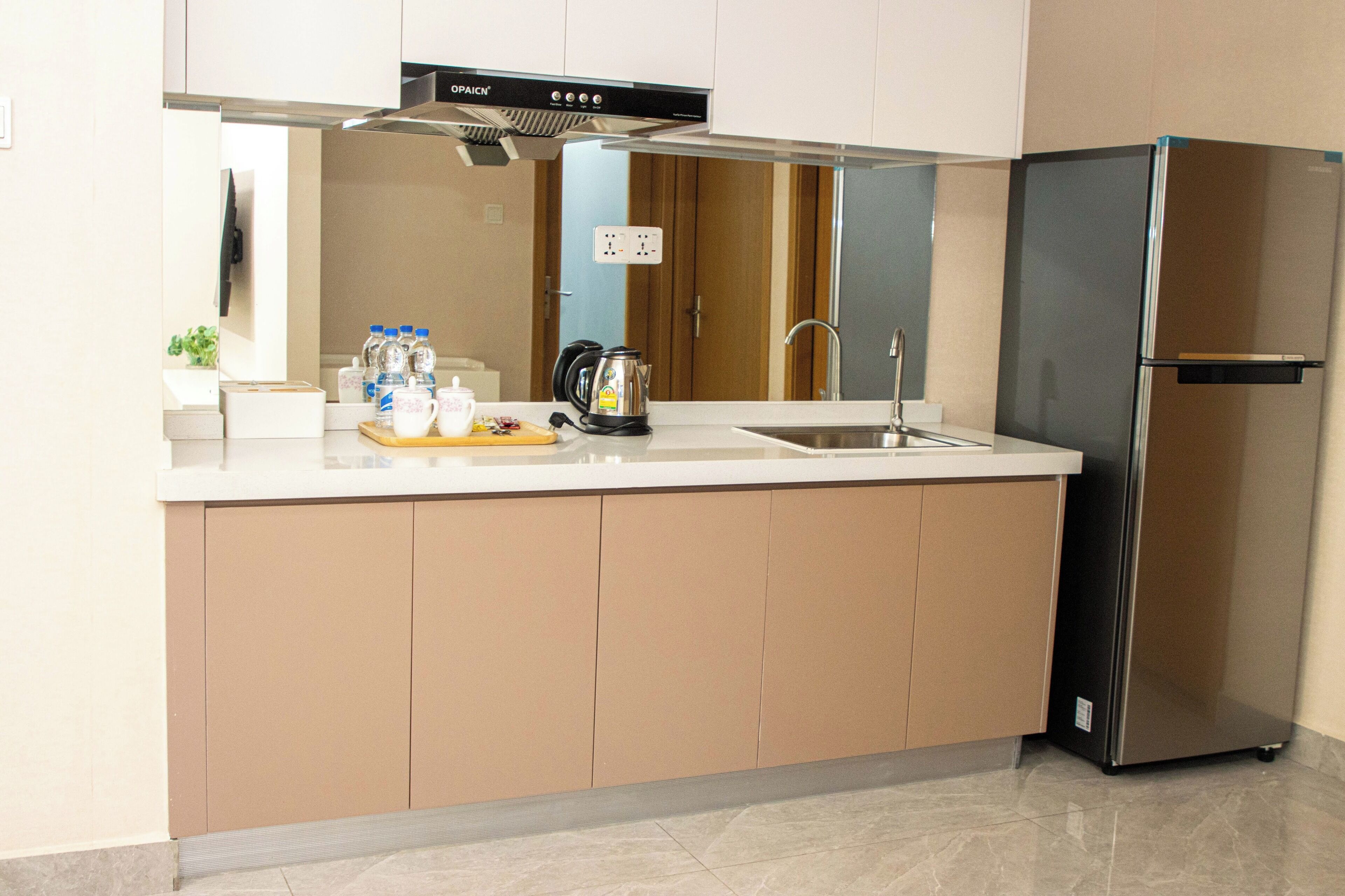 A modern kitchen with a stainless steel refrigerator, a built-in oven, and a coffee maker on the counter.