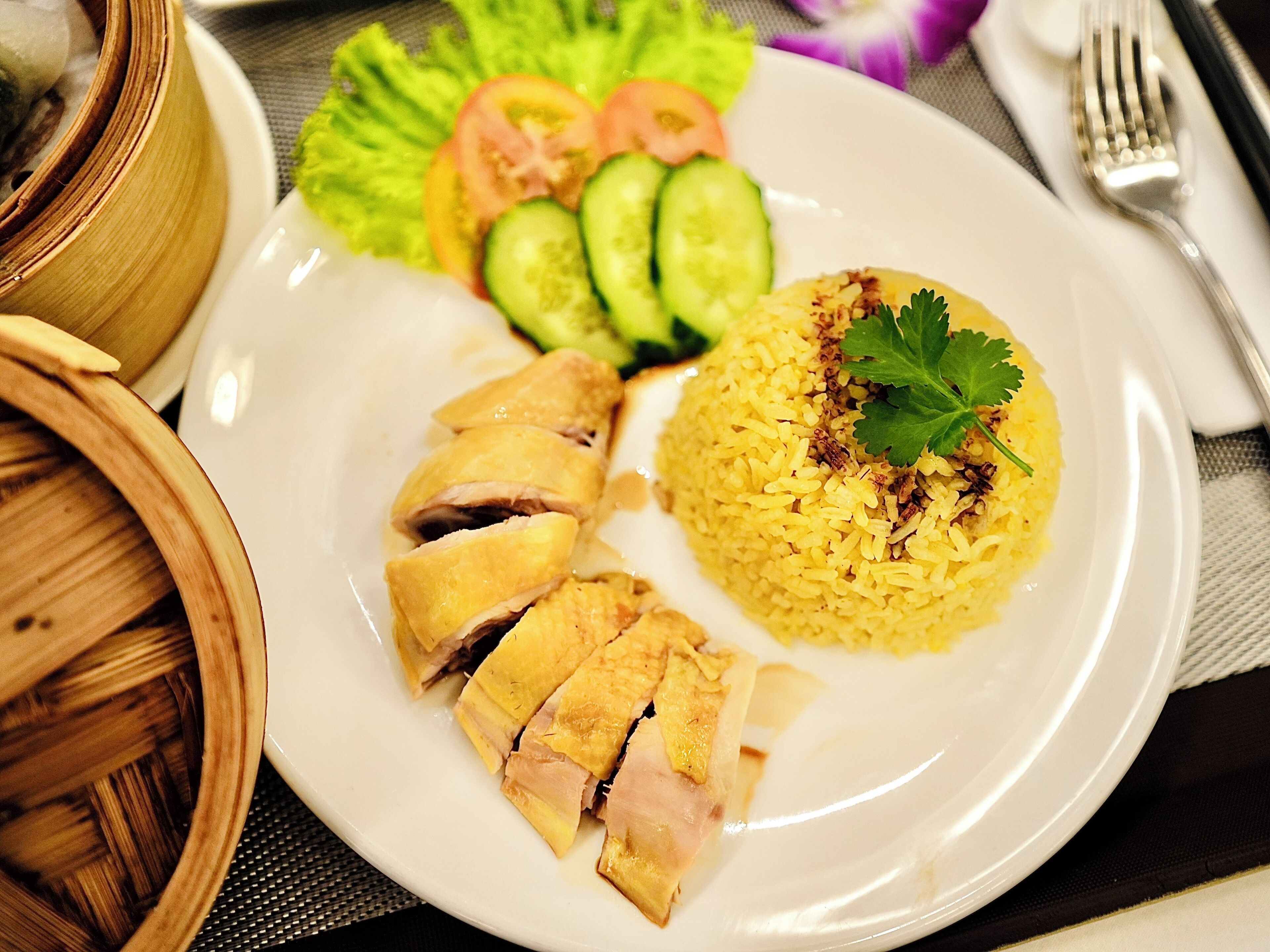 A plate with sliced chicken, yellow rice, and a side of vegetables.