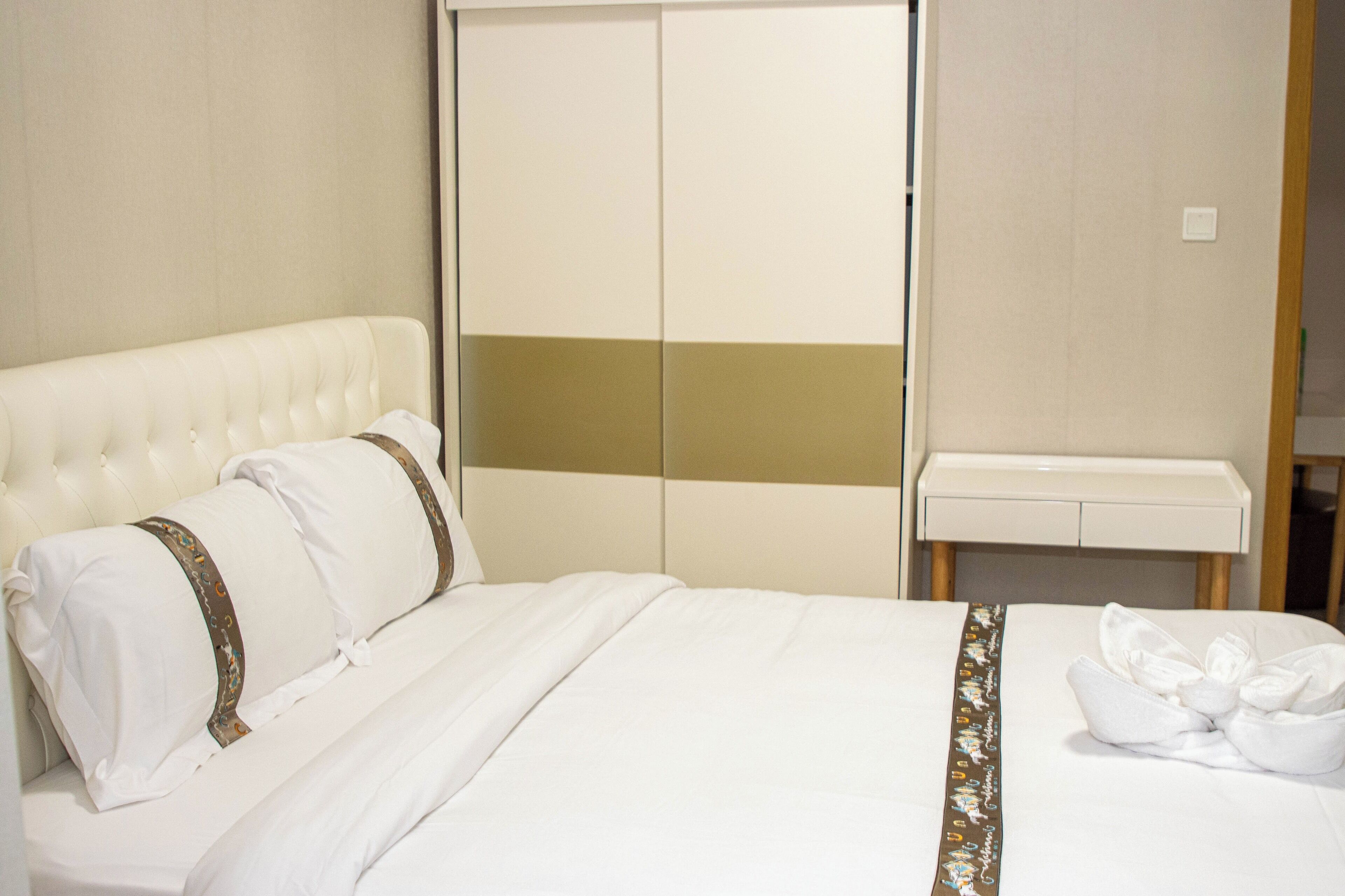 A hotel room with a large bed, a wardrobe, and a small table.