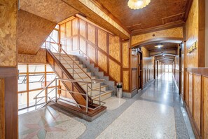 A wooden interior with a staircase, a long hallway, and a star-patterned floor. - Chatsuree Mansion (Ubon Ratchathani)