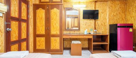 A hotel room with two beds, a wooden wardrobe, a desk with a mirror, a television, and a pink refrigerator.