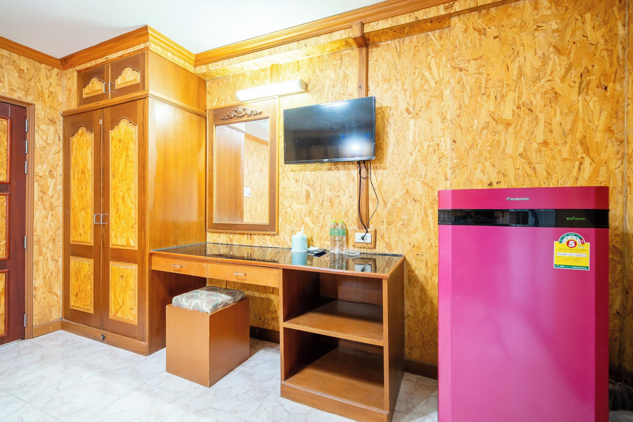 A kitchen with wooden cabinets, a countertop, a sink, a mirror, a television, and a pink refrigerator.