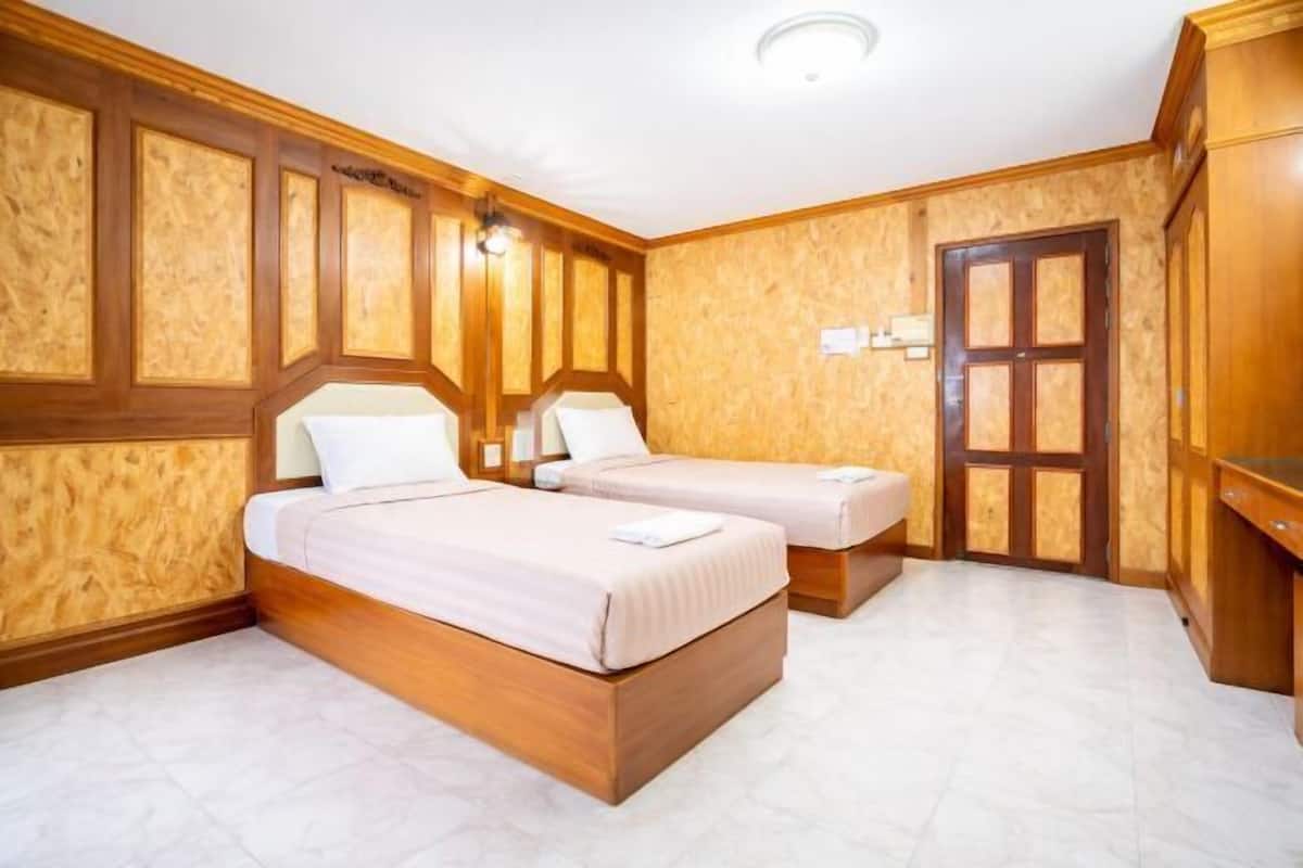 A hotel room with two beds, wooden paneling, a door, and a light fixture.