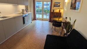 A compact kitchen with a dining area, a sofa, and a view through a glass door. - Charming 1 bed flat with extra study and sofabed (London)