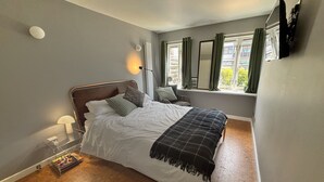 A bedroom with a bed, a bedside lamp, a window with curtains, and a view of the outside. - Charming 1 bed flat with extra study and sofabed (London)