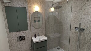A modern bathroom with a glass-enclosed shower, a freestanding toilet, a vanity with a mirror, and a built-in cabinet. - Charming 1 bed flat with extra study and sofabed (London)