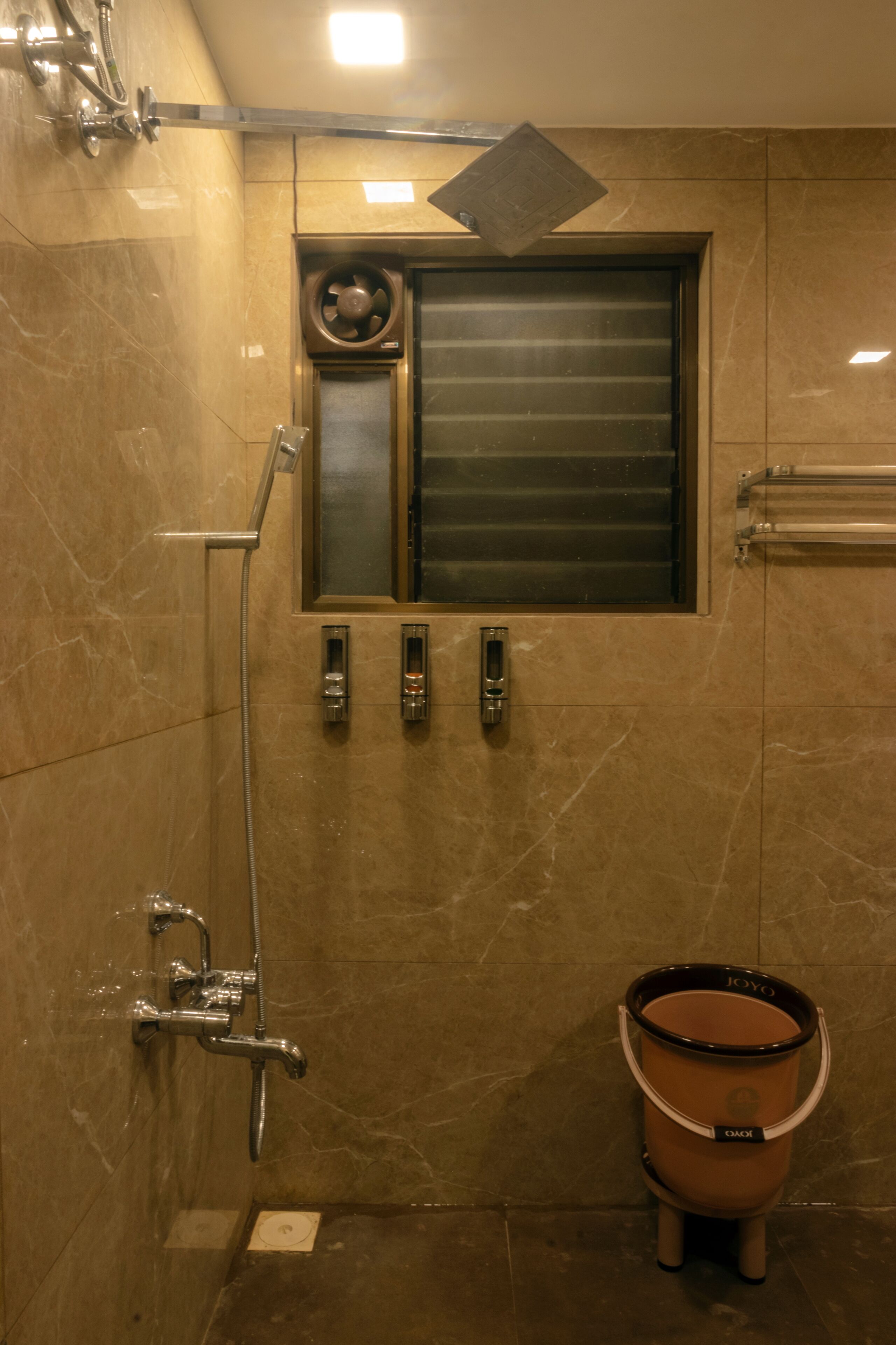 A bathroom with a shower, a window, and a towel rack.
