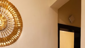 A hallway with a decorative golden wall piece, a chair, and a desk in the background. - Green Wood Villa By 97RoyalVista (Mawal)