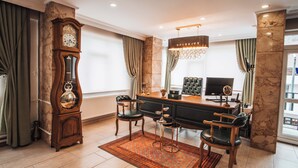 A spacious room with a large wooden clock, a desk with a computer, two chairs, and a chandelier. - Samsun Charme Hotel (Samsun)