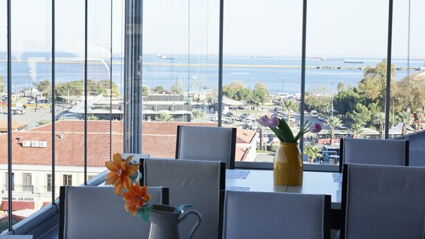 A dining area with a view of a body of water and buildings across the street. - Samsun Charme Hotel (Samsun)