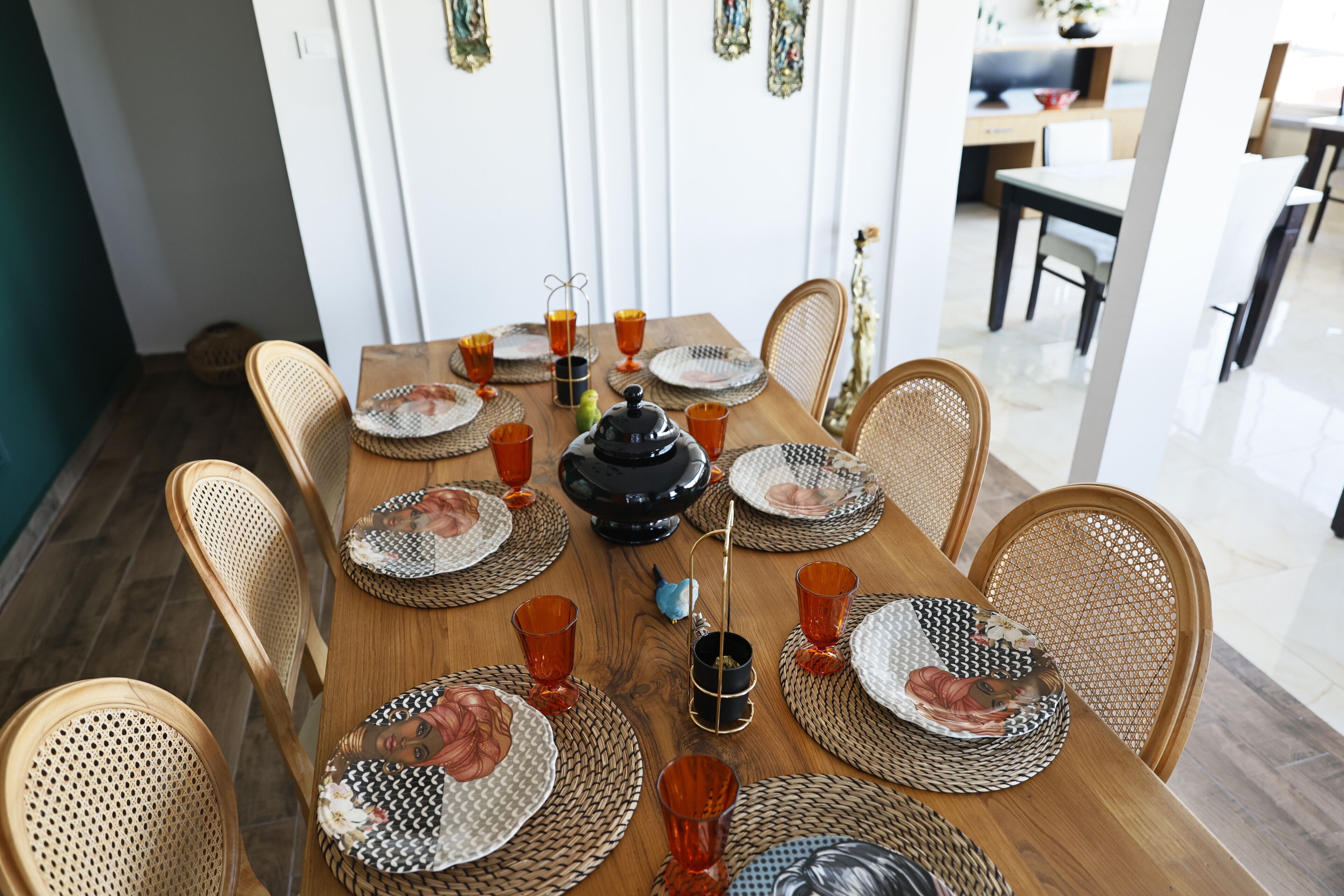 A dining table set with plates, glasses, and a teapot.