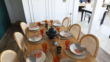 Una mesa de comedor servida con platos, vasos y una tetera.