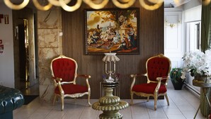 A luxurious room with two red upholstered chairs, a marble wall, and a large classical-style painting. - Samsun Charme Hotel (Samsun)