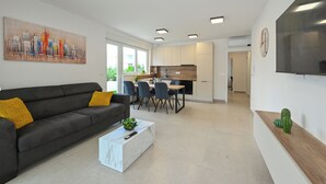 A modern living room with a sofa, coffee table, and a dining area with chairs and a table. - Two-bedroom apartment Break A1 next to the pool (Novalja)
