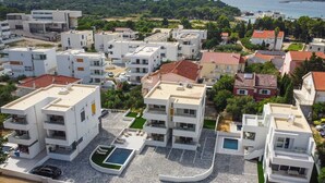 A modern residential area with multiple white buildings, a swimming pool, and a view of the sea. - Two-bedroom apartment Break A1 next to the pool (Novalja)