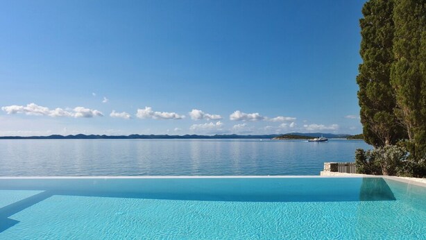 Una piscina infinita de aguas claras con vistas al mar y montañas lejanas.