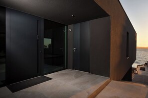 Una habitación moderna y minimalista con un amplio ventanal corredero que da a un balcón con vistas al mar.