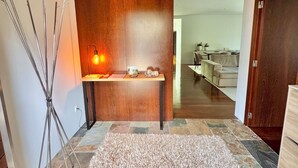 A modern interior with a stone-tiled floor, a wooden accent wall, a standing lamp, and a view into a dining area. - Villa Branco in the North of Portugal (Barcelos)