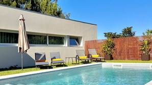 A swimming pool with clear water, surrounded by lounge chairs and a patio umbrella. - Villa Branco in the North of Portugal (Barcelos)