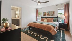 A bedroom with a bed, a ceiling fan, a nightstand, a lamp, a window with curtains, and artwork on the wall. - Newly Remodeled, Whimsical Retreat -  Viking Hot Tub, Ultimate Game Room, Massage Chair, BBQ (Round Rock)
