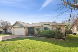 A single-story house with a garage, a covered front porch, and a well-maintained lawn. - Newly Remodeled, Whimsical Retreat -  Viking Hot Tub, Ultimate Game Room, Massage Chair, BBQ (Round Rock)
