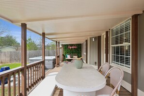 A covered patio with a table and chairs, a hot tub, and a neon sign. - Newly Remodeled, Whimsical Retreat -  Viking Hot Tub, Ultimate Game Room, Massage Chair, BBQ (Round Rock)