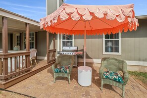 A patio with wicker chairs, a grill, and an umbrella. - Newly Remodeled, Whimsical Retreat -  Viking Hot Tub, Ultimate Game Room, Massage Chair, BBQ (Round Rock)