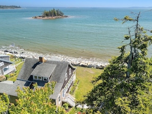 A coastal property with a large house, a dock, and a rocky shoreline.