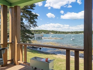 A wooden deck with a view of a lake, dock, and boats.