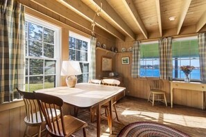 A wooden interior with a dining table, chairs, and large windows with curtains. - Marshall Point Cottage, classic 5-bedroom (Saint George)