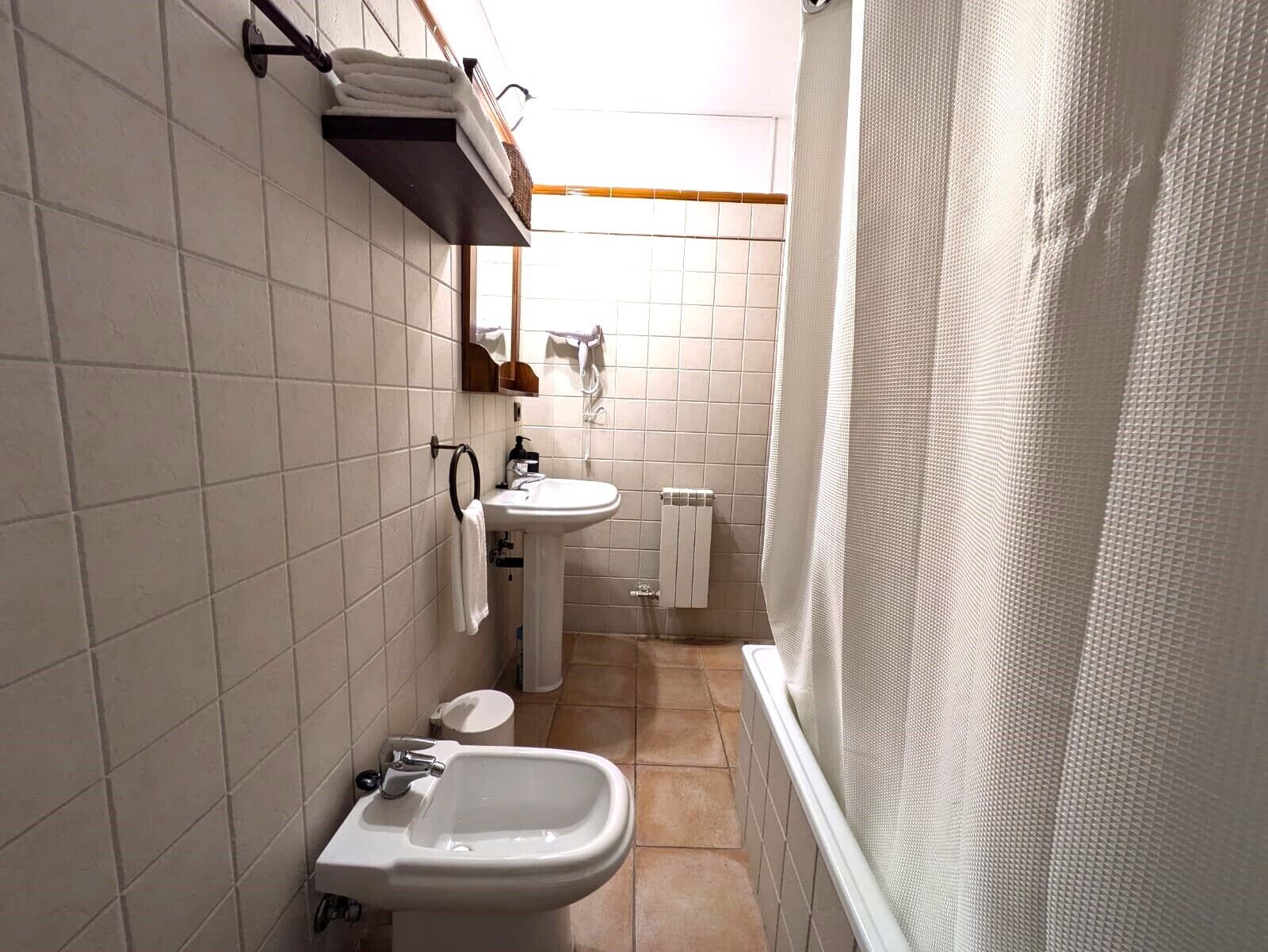 Ein kleines Badezimmer mit Waschbecken, Bidet, Toilette und Duschbereich.